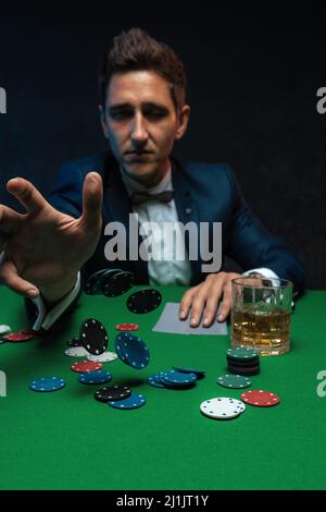 Pokerspieler wirft Chips auf grünen Tisch im Casino. Stockfoto