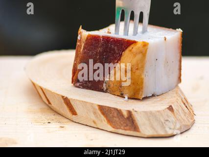 Ein Stück Schmalz oder Speck, mit einer Gabel auf einem Holzschneidebrett, aus der Nähe Stockfoto