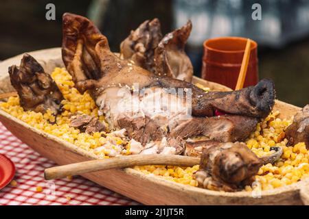 Gegrilltes Fleisch Schweinekopf auf einem traditionellen Holzteller auf einem Tisch bei einem regionalen Straßenmarktfest Stockfoto