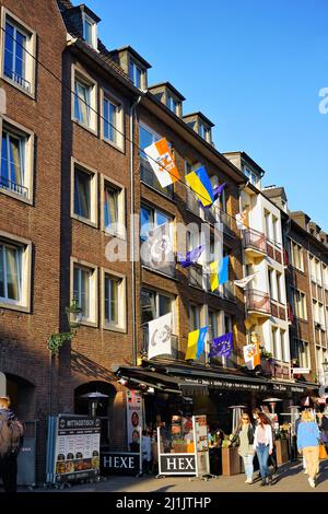 Düsseldorfer Altstadt mit verschiedenen lokalen und internationalen Flaggen (Düsseldorfer Flagge, Ukraine-Flagge, EU-Flagge) vor einem Restaurant. Stockfoto