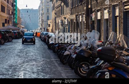 Ein Bild einer Straße in Rom mit einer langen Reihe von Motorroller auf der rechten Seite. Stockfoto