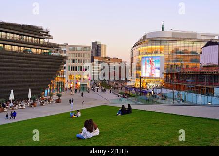 Weitwinkelansicht des neugebauten Kö-Bogen II-Komplexes in der Düsseldorfer Innenstadt an einem Frühlingsabend. Es hat ein begehbares, dreieckiges grünes Rasendach. Stockfoto