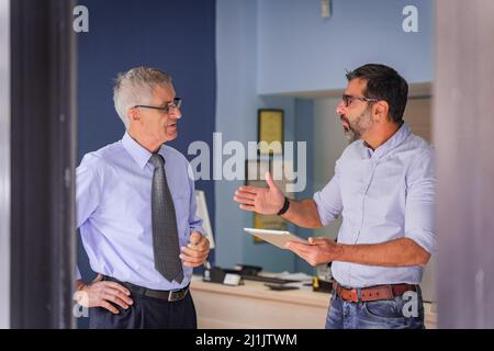 Zwei ältere Geschäftsleute führen in ihrem Büro eine Diskussion über das Treffen Stockfoto