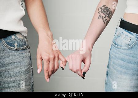 Nahaufnahme von unkenntlichen Lesben, die pinkige Finger als Symbol der Liebe zusammenhalten Stockfoto