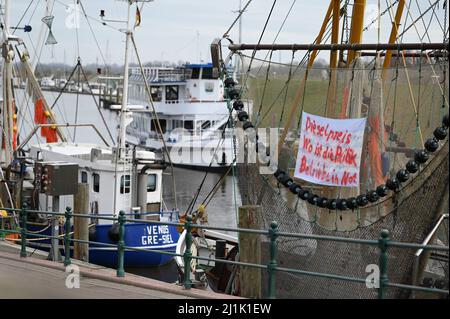 Greetsiel, Deutschland. 26. März 2022. Ein Banner mit der Aufschrift „Dieselpreis. Wo ist die Richtlinie? Unternehmen in Not hängen an einem Angelschneider im Hafen. Aufgrund der enormen Preiserhöhung von Schiffsdiesel lohnen sich Fischereifahrten auf der Nord- und Ostsee derzeit nicht für Fischer. Die Kutter bleiben oft in den Häfen. Quelle: Lars Klemmer/dpa/Alamy Live News Stockfoto