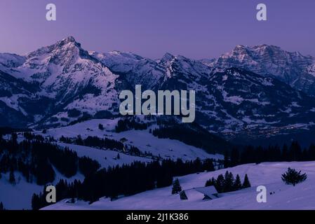 Im Winter leuchten die schneebedeckten Berggipfel der Glarner Alpen in der Schweiz bei Sonnenaufgang Stockfoto