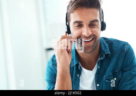 Hes einen so freundlichen Charakter. Aufnahme eines attraktiven jungen Callcenter-Agenten, der in seinem Büro arbeitet. Stockfoto