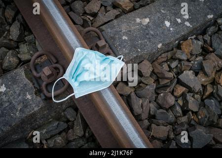 Auf den Gleisen liegt eine medizinische Gesichtsmaske Stockfoto