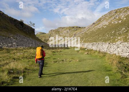 Person, die im trockenen Tal in der Nähe von Malham Cove, Yorkshire Dales, England, Großbritannien, läuft Stockfoto