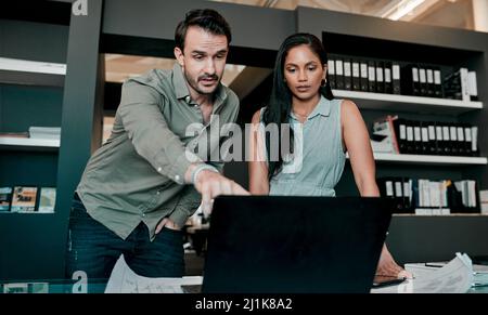 Lassen Sie uns diesen Abschnitt besprechen. Aufnahme von zwei jungen Geschäftsleuten, die etwas auf einem Laptop diskutieren. Stockfoto