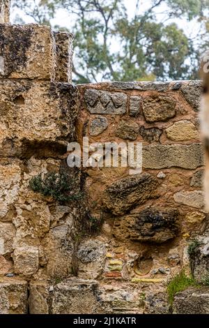 Die Römischen Bäder von Salamis zeigen die einzelnen Bauphasen an dieser Wand: helle Kalksteinblöcke, rötliches Ziegelmaterial und die gleiche eingravierte Zickzack-Maurerzeichen, die an der angrenzenden Wand zu sehen ist. Der Badekomplex liegt nahe Yeni Boğaziçi, Türkische Republik Zypern (TRNC). Stockfoto