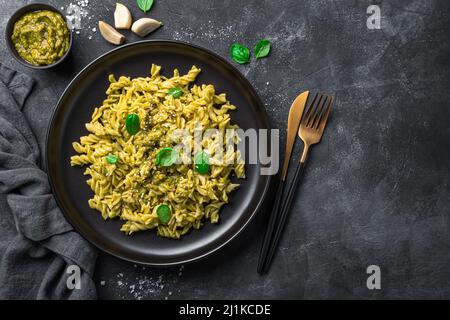 Pasta mit Basilikum-Pesto-Sauce auf schwarzem Hintergrund. Draufsicht, Kopierbereich. Stockfoto
