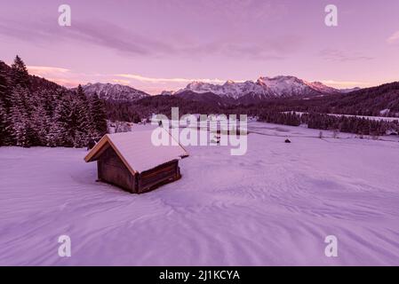 Alpenglow in der Dämmerung an der verschneiten Winterlandschaft am Geroldsee und dem Panorama des Karwendelgebirges, Bayern, Deutschland Stockfoto