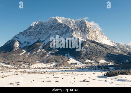 Das Wettersteinmassiv mit der Zugspitze über dem schneebedeckten Ehrwalder Becken in der Morgensonne im Winter, Tirol, Österreich Stockfoto