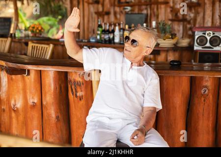 Glücklicher älterer Mann, der in der Strandbar sitzt Stockfoto