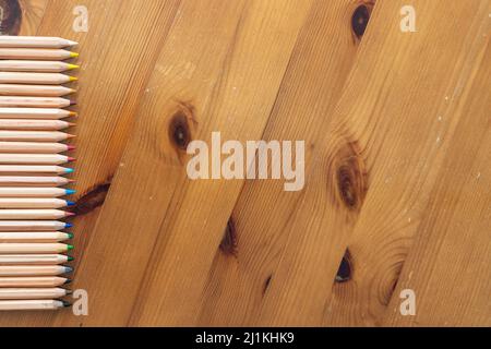 Ein flaches Lay-Bild von Aquarellstiften auf einem Hintergrund im Holzstil Stockfoto