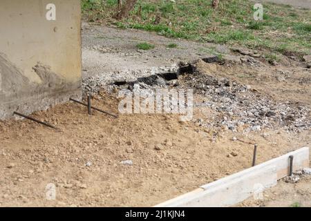 Vorbereitung des Blindbereichs des Fundaments. Grundlegende Schalungsmarkierung. Sackbereich Bau in der Nähe des Hauses. Hammer Eisenarmatur am Fuß des Hauses Stockfoto