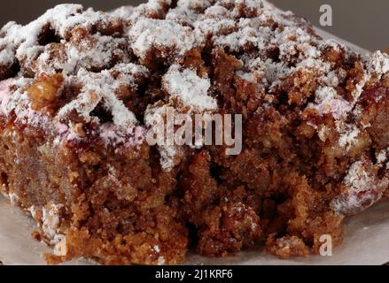 Nahaufnahme, Makroaufnahme eines Stückes Raselbeerkarotten-Krümelkuchen, bestreut mit Puderzucker, die Innenseite nach dem Einschneiden deutlich sichtbar Stockfoto