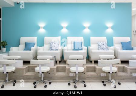Nagelstudio-Innenausstattung, Vorderansicht moderner Pediküre-Sessel im Maniküre-Shop oder Spa-Raum. Im Inneren helles Beauty-Studio mit blau-weißem Design. Cle Stockfoto