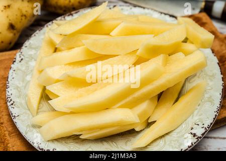 Gericht mit rohen Rohrkartoffeln, um pommes frites zu machen. Gehackt oder hohe Ansicht. Nahaufnahme. Stockfoto