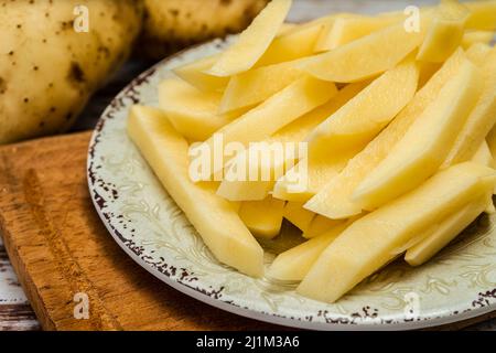 Gericht mit rohen Rohrkartoffeln, um pommes frites zu machen. Gehackt oder hohe Ansicht. Nahaufnahme. Stockfoto