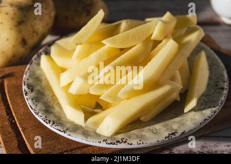 Gericht mit rohen Rohrkartoffeln, um pommes frites zu machen. Gehackt oder hohe Ansicht. Nahaufnahme. Stockfoto