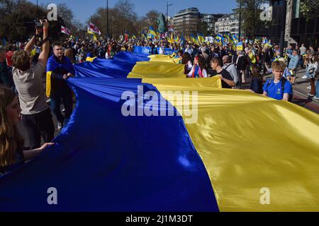 London, England, Großbritannien. 26. März 2022. Demonstranten halten in der Park Lane eine riesige ukrainische Flagge, während die Londoner Stände mit der Ukraine marschieren. Tausende von Menschen marschierten aus Solidarität mit der Ukraine von der Park Lane zum Trafalgar Square, während Russland seinen Angriff fortsetzt. (Bild: © Vuk Valcic/ZUMA Press Wire) Stockfoto