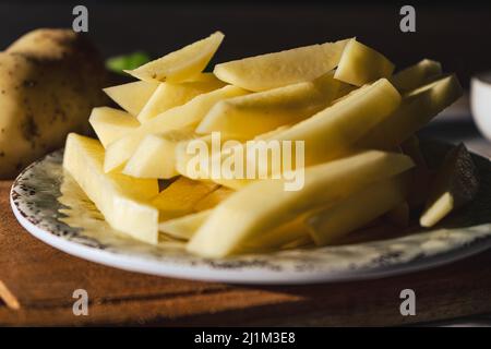 Gericht mit rohen Rohrkartoffeln, um pommes frites zu machen. Gehackt oder hohe Ansicht. Nahaufnahme. Stockfoto