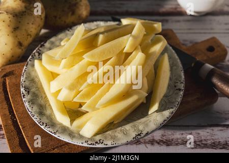 Gericht mit rohen Rohrkartoffeln, um pommes frites zu machen. Gehackt oder hohe Ansicht. Nahaufnahme. Stockfoto