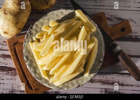 Gericht mit rohen Rohrkartoffeln, um Pommes frites zu machen. Draufsicht. Nahaufnahme. Stockfoto