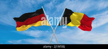Zwei gekreuzte Flaggen Bundesrepublik Deutschland und Belgien winken im Wind bei bewölktem Himmel. Konzept der Beziehung, Dialog, Reisen zwischen zwei Gräfin Stockfoto