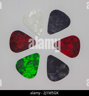 Gitarren-Picks in einem Kreis platziert, um ein Interessantes Muster zu bilden. Weißer Hintergrund unter Picks. Stockfoto