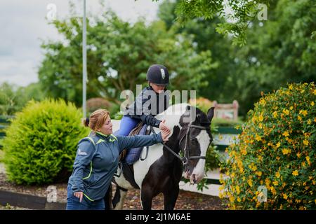 Mein Trainer hilft mir dabei, erfolgreich zu sein. Aufnahme eines Reittrainers, der einem jungen Mädchen beibringt, wie man im Freien auf einem Pferd reitet. Stockfoto