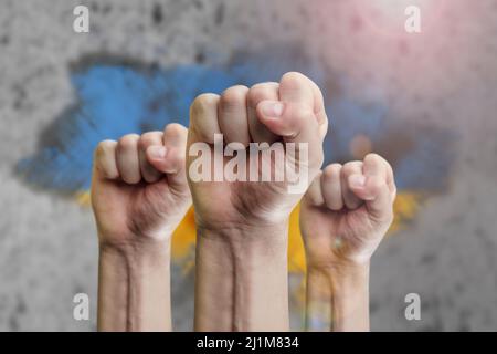 Unterstützung der Ukraine und Solidarität. Hilfe für das ukrainische Volk in Kriegszeiten. Fäuste als Symbol der Unterstützung vor dem Hintergrund der ukrainischen Flagge Stockfoto