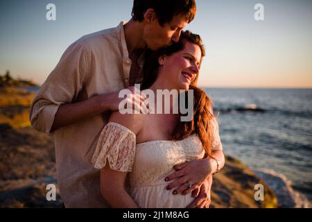 Ehemann küssend schwanger Frau am Strand bei Sonnenuntergang in San Diego Stockfoto