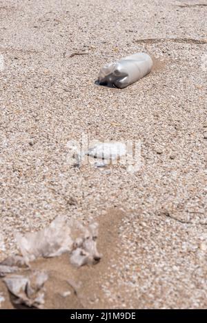 Plastikflasche liegt auf dem Sand in Strandnähe. Kümmern wir uns um den Planeten Stockfoto