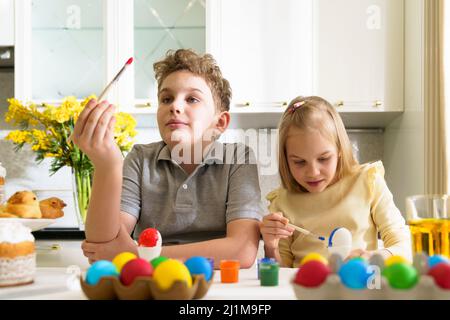 Süße Brüder und Schwester färben ostereier. Stockfoto