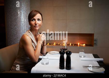 Shes plante den perfekten Abend für ihren Mann. Eine kurze Aufnahme einer attraktiven Frau, die in einem Restaurant auf ihr Date wartet. Stockfoto