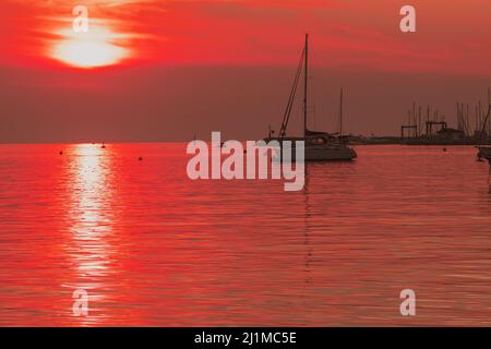 Sonnenaufgang an der Küste. In der Silhouette der Schiffe im Hafen. Selektiver Fokus Stockfoto