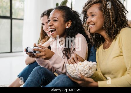 Vereinigte multirassische junge Frauen spielen Videospiele mit Konsole zu Hause Stockfoto