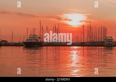 Sonnenaufgang an der Küste. In der Silhouette der Schiffe im Hafen. Selektiver Fokus Stockfoto