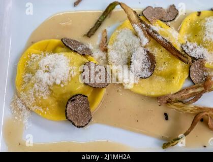 Italienische Küche, frisch hausgemachte rote Kartoffel gefüllte Pasta Tortellacci oder Ravioli Knödel mit Sommer schwarzen Trüffel und knusprigen grünen Spargel und geriebt Stockfoto