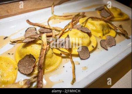 Italienische Küche, frisch hausgemachte rote Kartoffel gefüllte Pasta Tortellacci oder Ravioli Knödel mit sommerlichen schwarzen Trüffeln und knusprigen grünen Spargel, Parma, E Stockfoto