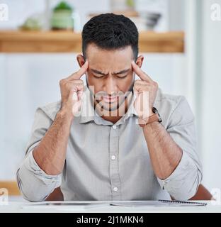 Mein Kopf fühlt sich an, als würde er explodieren. Aufnahme eines jungen Geschäftsmannes, der bei der Arbeit Kopfschmerzen hat. Stockfoto