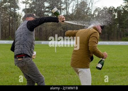 Raeford, North Carolina, USA. 26. März 2022. DOUG PAYNE, links, sprüht während der Preisverleihung beim Carolina International CCI and Horse Trial, 26. März 2022, im Carolina Horse Park in Raeford, North Carolina, mit Champagner. Der Carolina International CCI and Horse Trial ist einer der führenden Wettkampfwettbewerbe für nationale und internationale Wettkampfkombinationen in Nord AmericaÃs und veranstaltet CCI1*-S bis CCI4*-S und National Levels of Training through Advanced. (Bild: © Timothy L. Hale/ZUMA Press Wire) Stockfoto