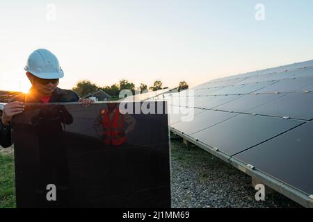 Techniker hebt die Solarzelle, um die beschädigte zu ersetzen, Alternative Energie, um die Energie der Welt zu sparen, Photovoltaikmodul Idee für sauber Stockfoto