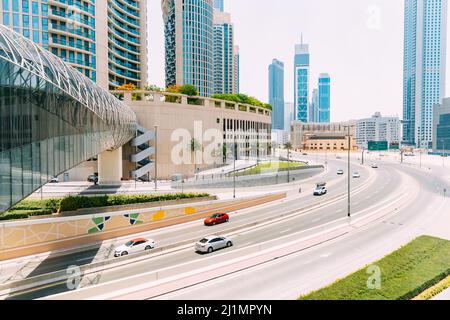 Autos bewegen sich auf der Straße zwischen gläsernen Wolkenkratzern in Dubai. Verkehr auf der Straße in Dubai. Autos bewegen sich auf der Straße. Modern mit Wolkenkratzern Architektur von Stockfoto
