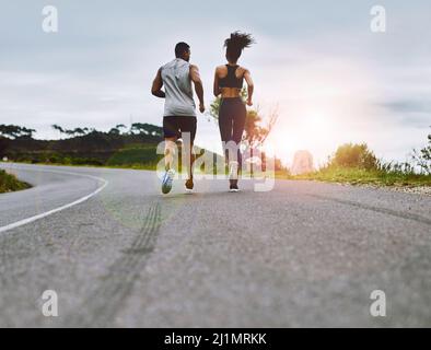 Zusammen in Topform bleiben. Rückansicht eines sportlichen jungen Paares, das gemeinsam im Freien trainiert. Stockfoto