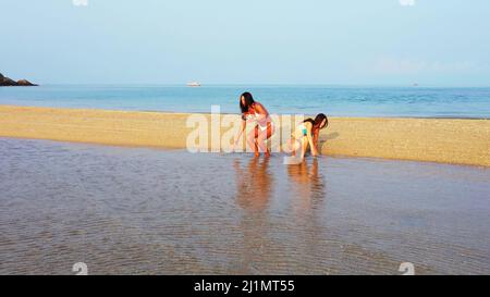 Zwei kaukasische hübsche Frauen im Bikini, die am Strand auf Koh Samui, Thailand, liegen und spielen Stockfoto