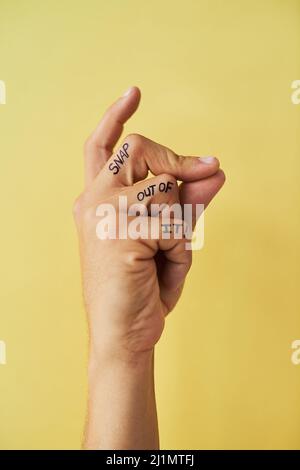 Rasten Sie heraus. Studioaufnahme eines nicht erkennbaren Mannes, der seine Finger vor einem gelben Hintergrund schnappt. Stockfoto